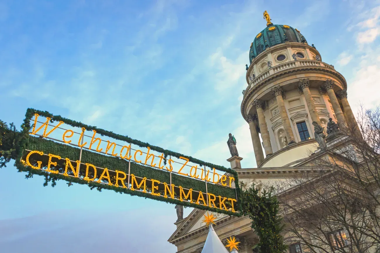 WeihnachtsZauber Gendarmenmarkt entrance sign with the French Cathedral behind in Berlin