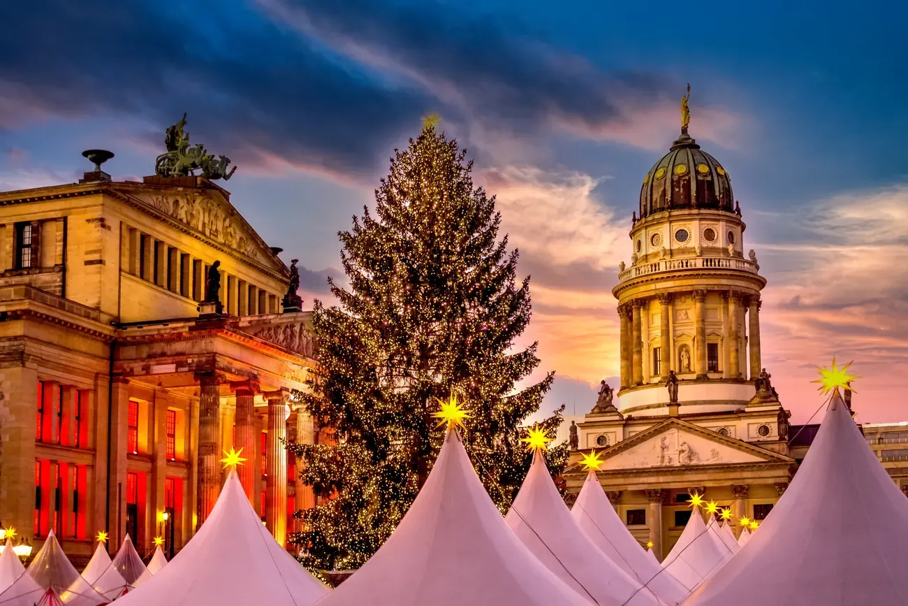 The white tents, the Christmas tree, the Konzerthaus and the French Cathedral of the WeihnachtsZauber on Gendarmenmarkt in Berlin at dusk
