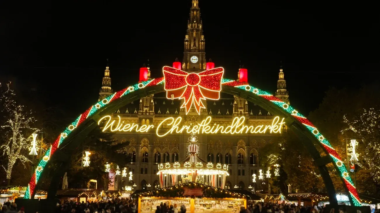 Illuminated Wiener Christkindlmarkt arch in front of Vienna City Hall on Rathausplatz at night