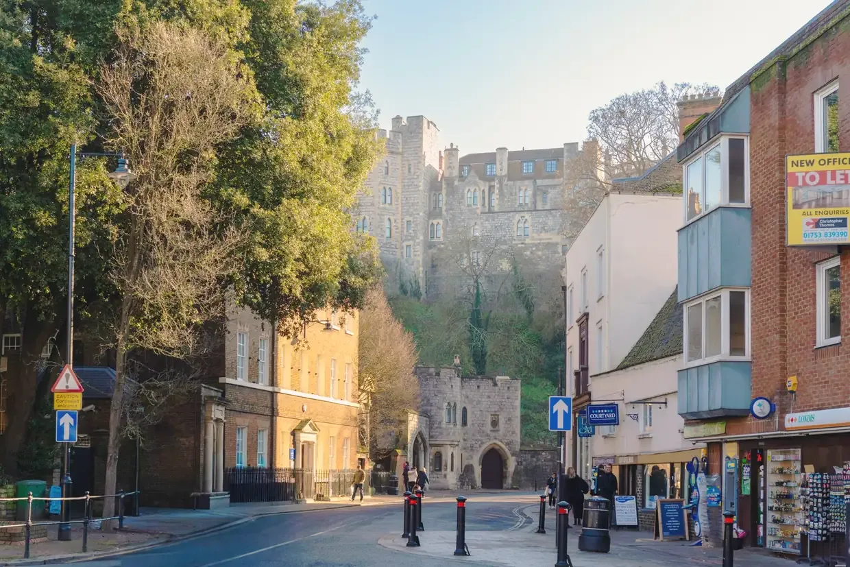 A street in Windsor town centre with the walls and towers of Windsor Castle above, England