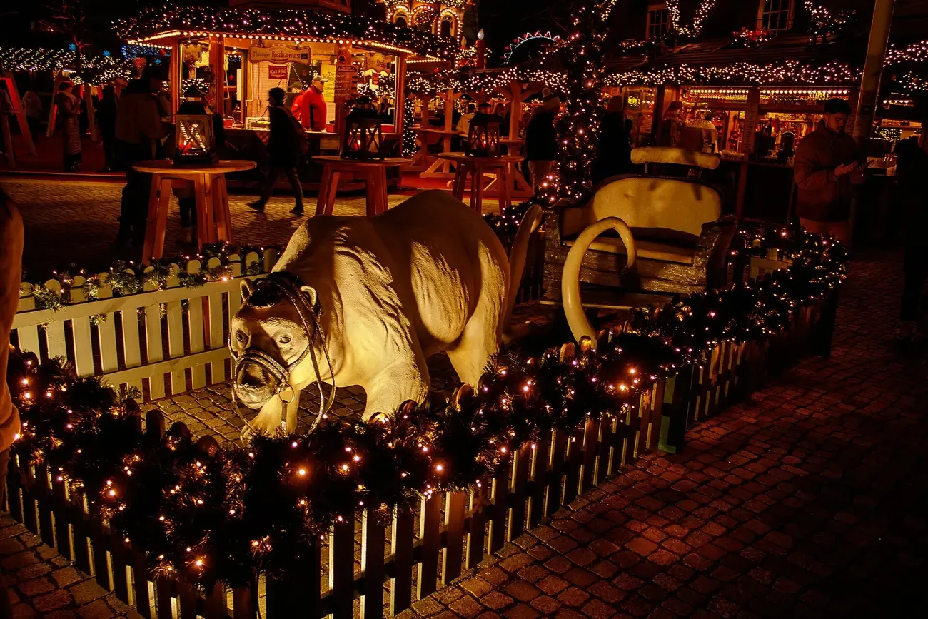 A lit carousel figure and wooden huts at the winter market by the Humboldt Forum, Berlin