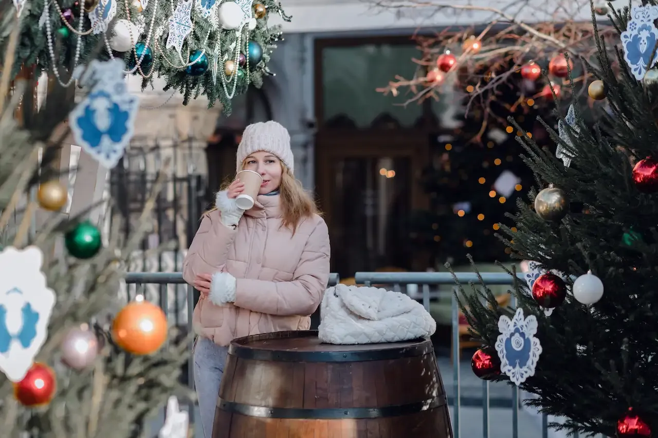 A woman drinking a hot drink at a Christmas market