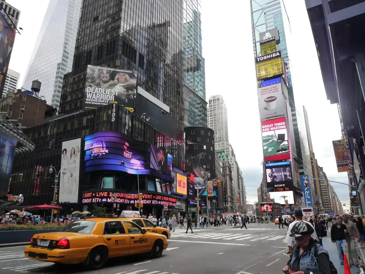 A yellow cab crossing Times Square below the advertising screens in New York City
